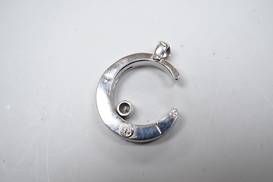 A diamond pendant, designed as a crescent moon accented with two collet-set brilliant-cut diamonds totalling approximately 0.20 carats, one sliding up and down the inner curve of the moon, length 2.6cm, mounted in platin